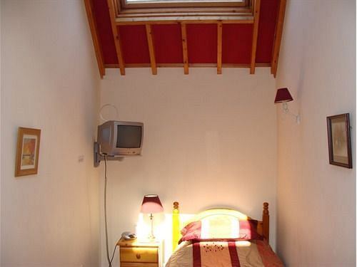 Single guest room with beamed ceiling and wall-mounted TV